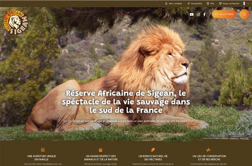 Lion majestueux sur herbe avec publicité Réserve Africaine de Sigean, options de navigation visibles.